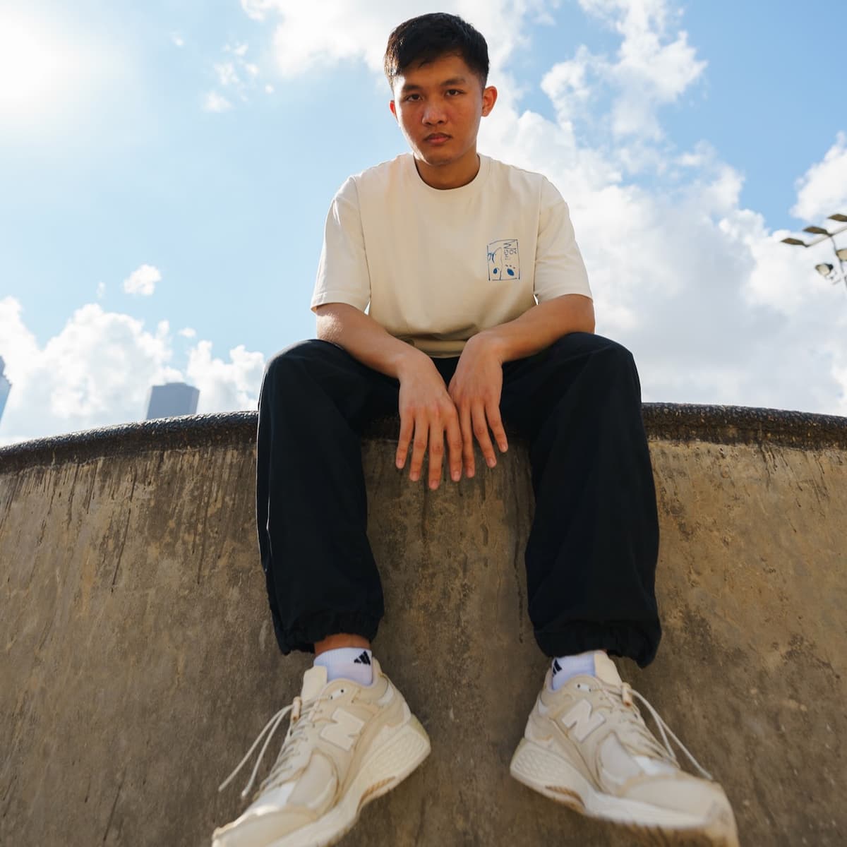 A guy sitting on a ledge, wearing the 5:06 Train Shirt